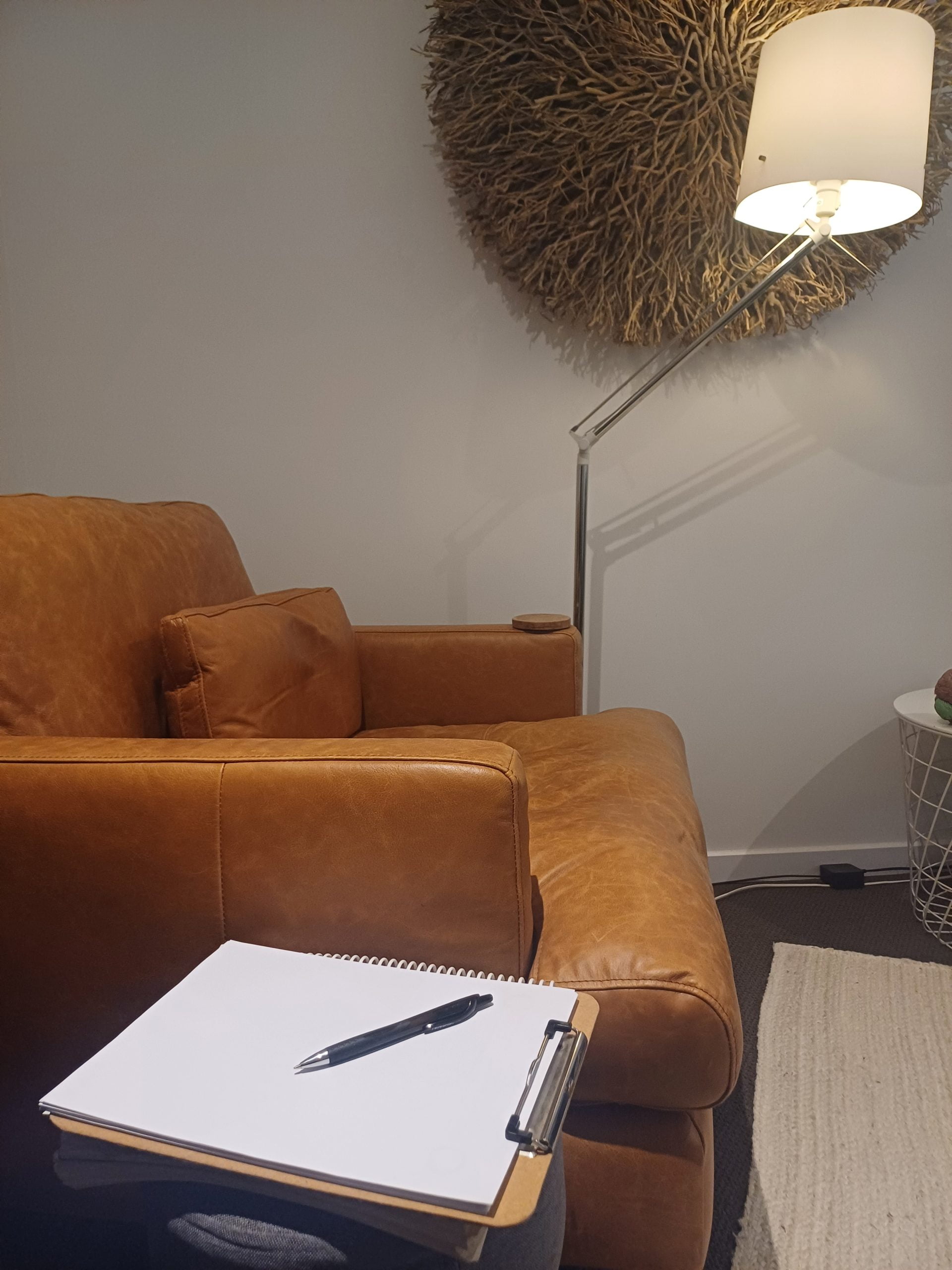 Modern lounge with leather sofa, lamp, and sketchbook.