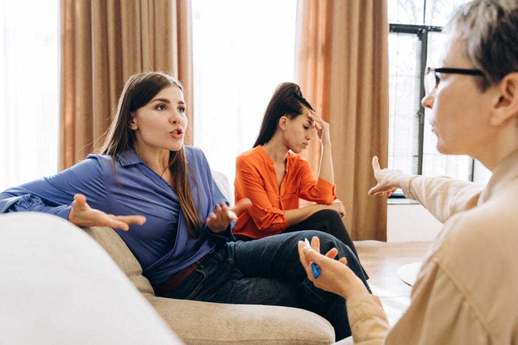Psychologist mediating conflict between two arguing women during therapy session