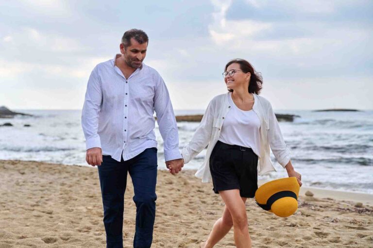 Couple holding hands, walking on a beach