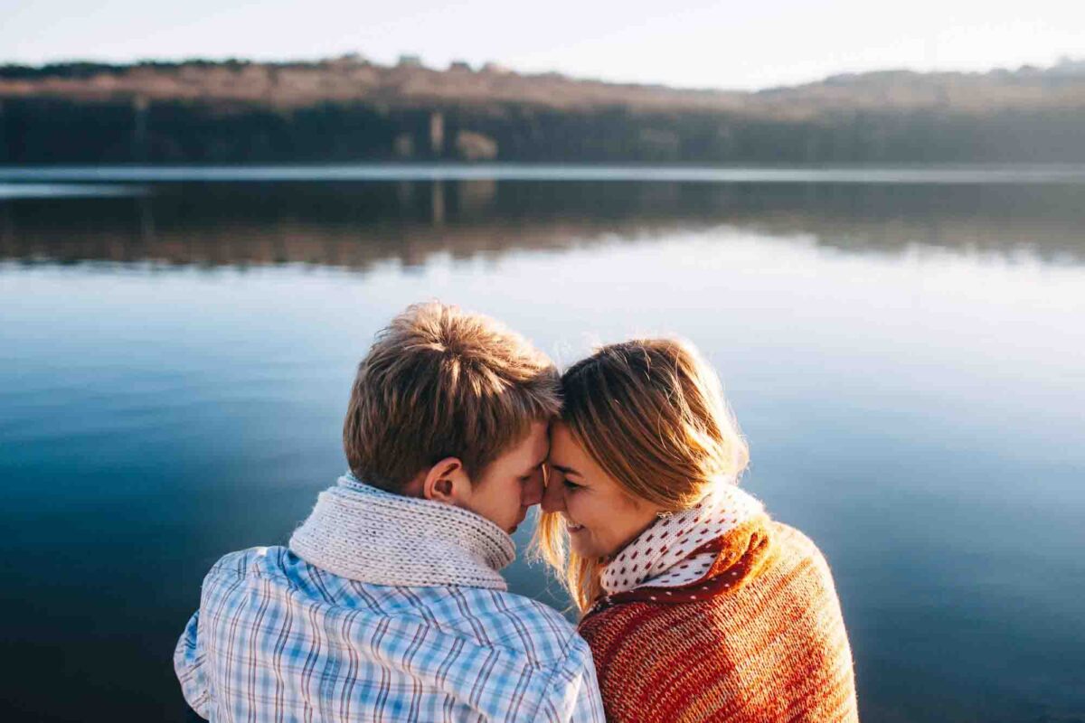 Couple by peaceful lake embracing affectionately.